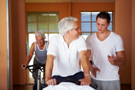 Fitness coach explaining spinning exercises to two senior people